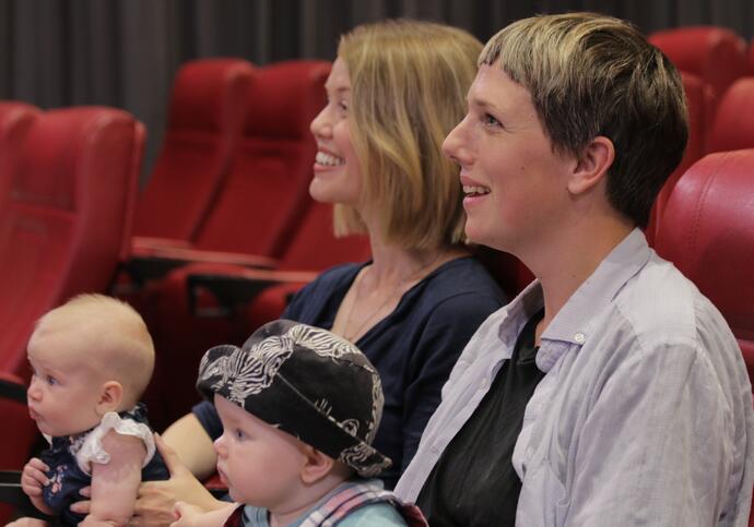 Photo of two women with babies watching a film in the Barbican cinema